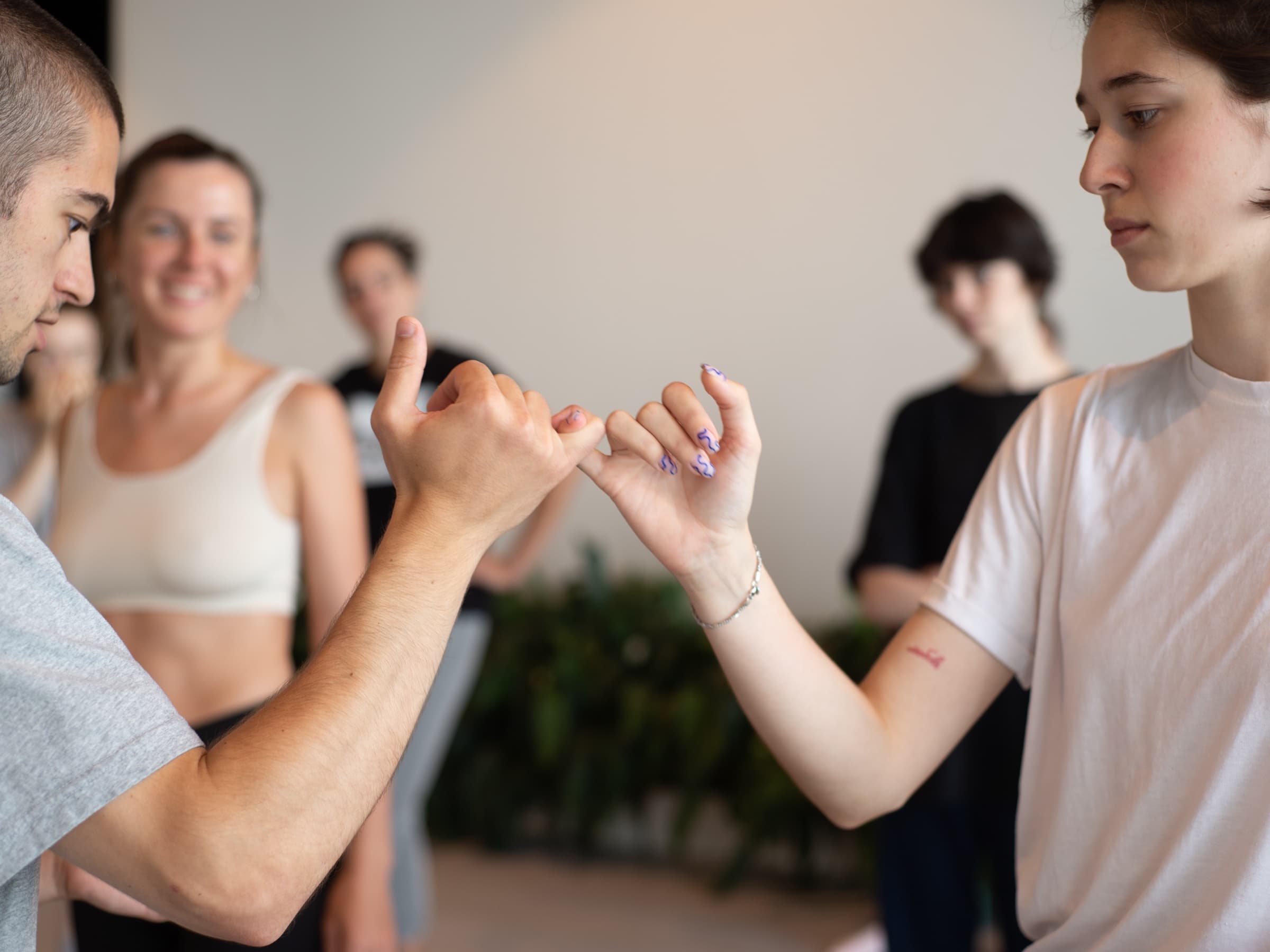 Two workshop participants connect their little fingers while others watch behind them.