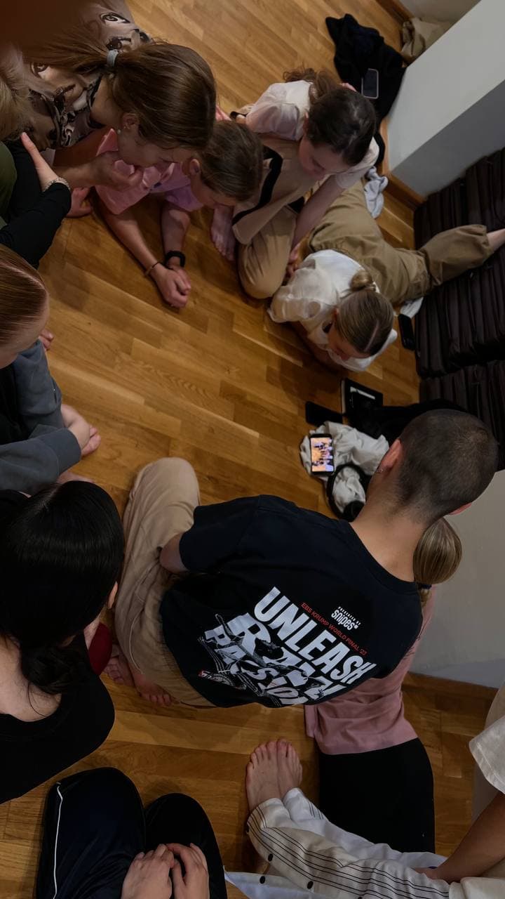 Participants gather closely around a shared point of attention during a Green Theatre laboratory.