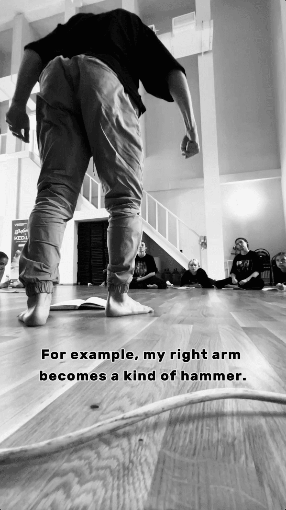 A facilitator demonstrates an embodied example while participants observe from the studio floor.