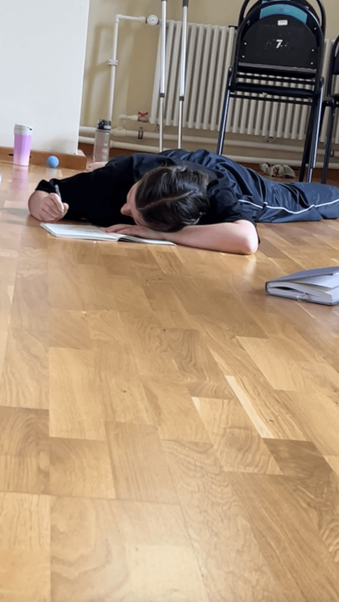 A participant writes in a notebook while lying on the studio floor.