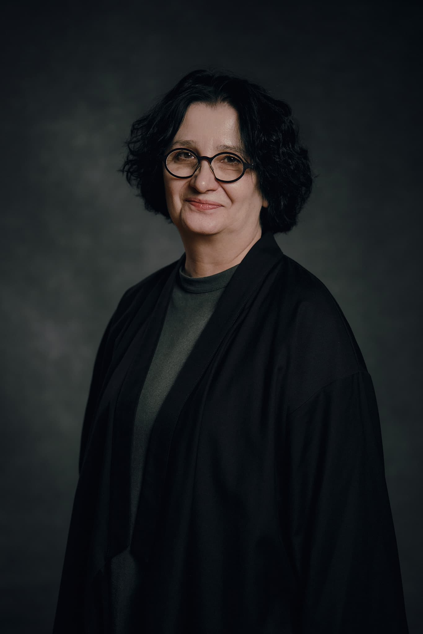 Costume designer Irena Belousova in a dark jacket and round glasses.