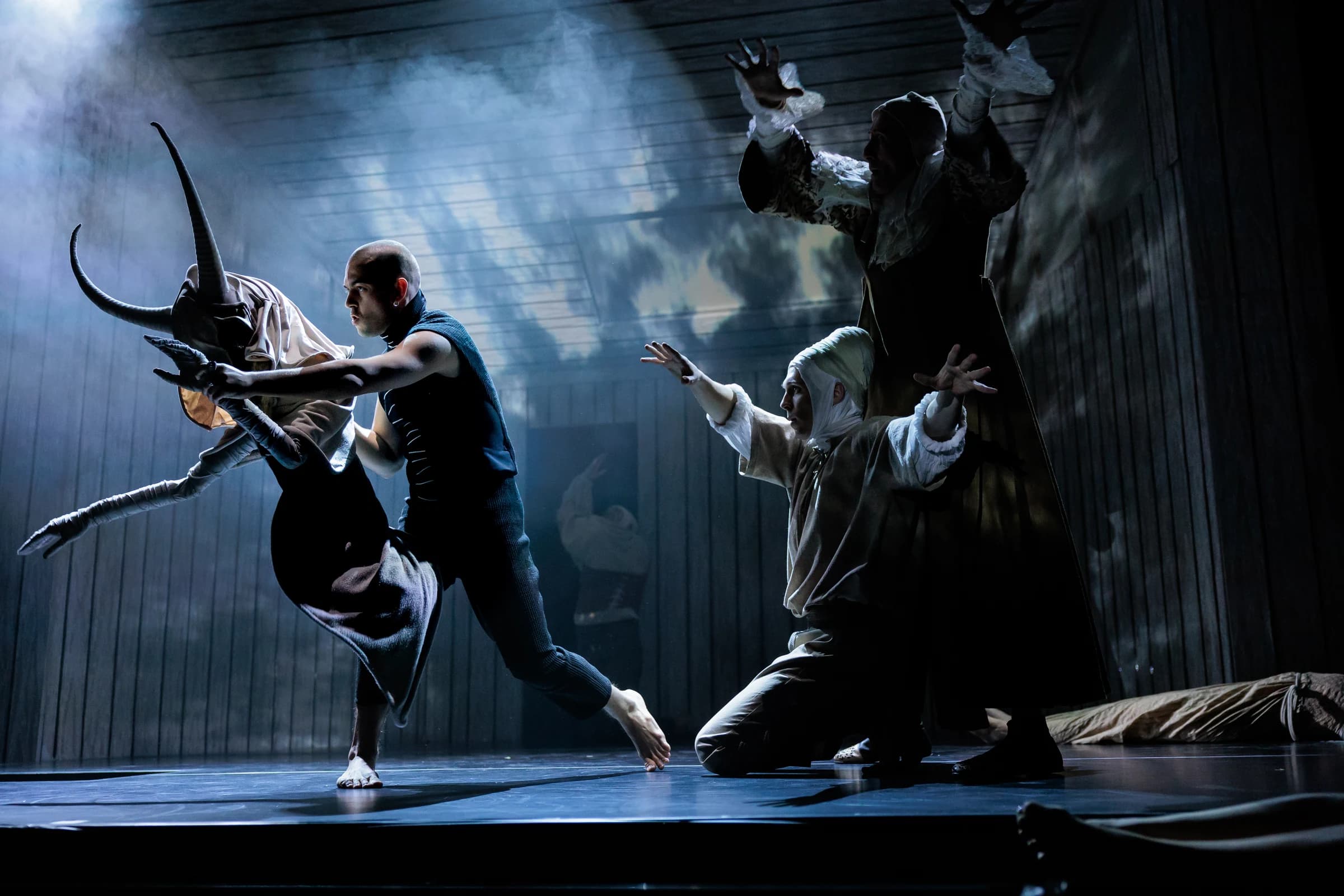 Mephistopheles moves with a horned figure while the ensemble responds on stage.