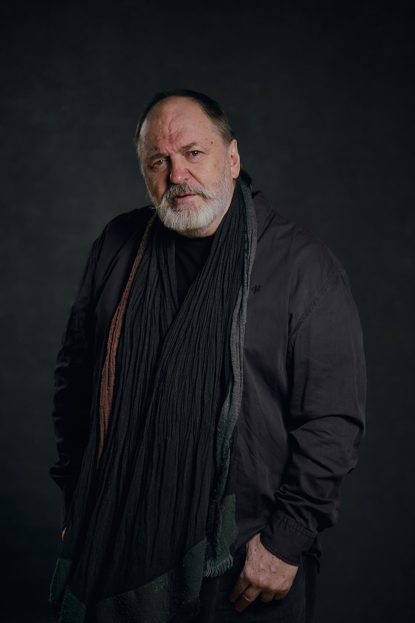 Production designer Viktor Nikonenko wearing a dark jacket and scarf against a dark background.