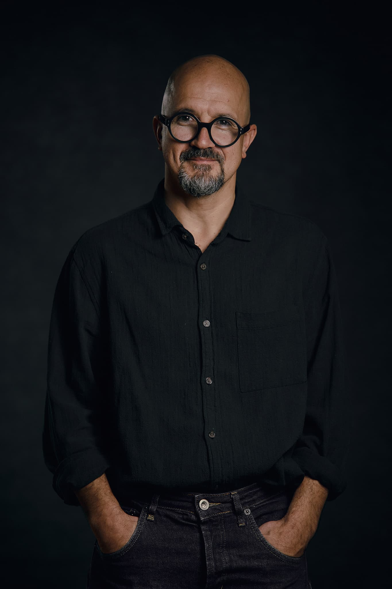 Stage director and choreographer Egor Druzhinin in a dark shirt and round glasses.