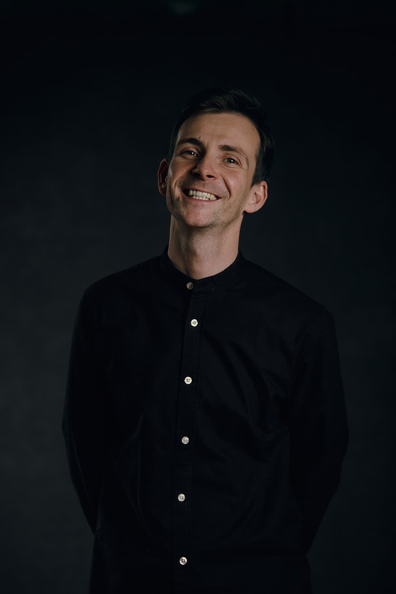 Director of theatrical production Maxim Kustov smiling in a dark shirt.