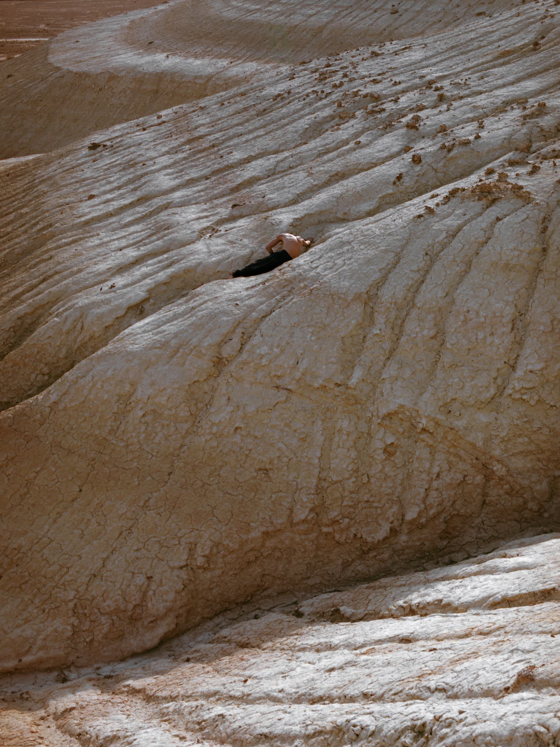 Kolya Bagdasaryan lying within the layered pale rock formations of Bozzhyra.