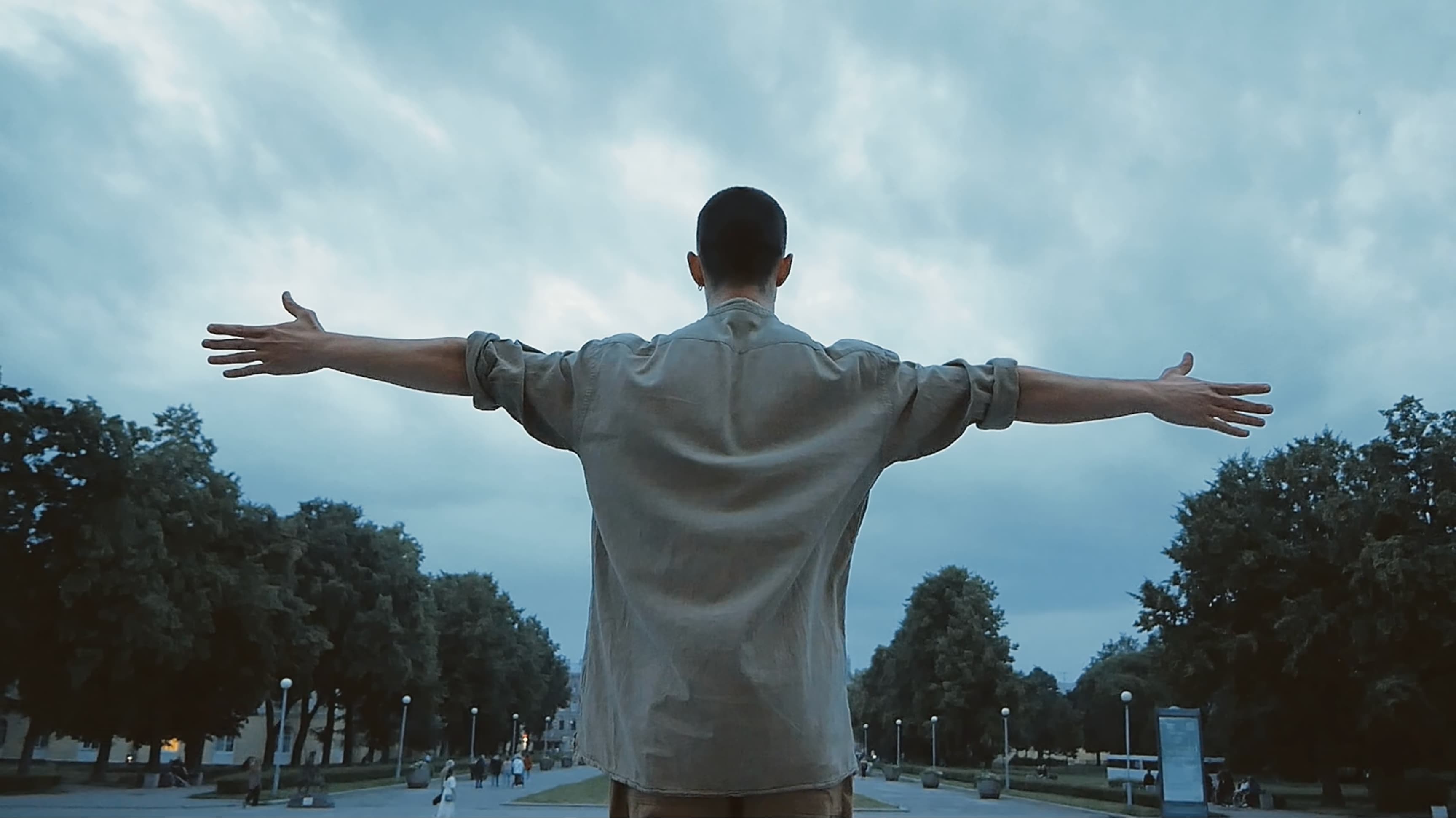 Kolya Bagdasaryan standing outdoors with his back to the camera and his arms outstretched.