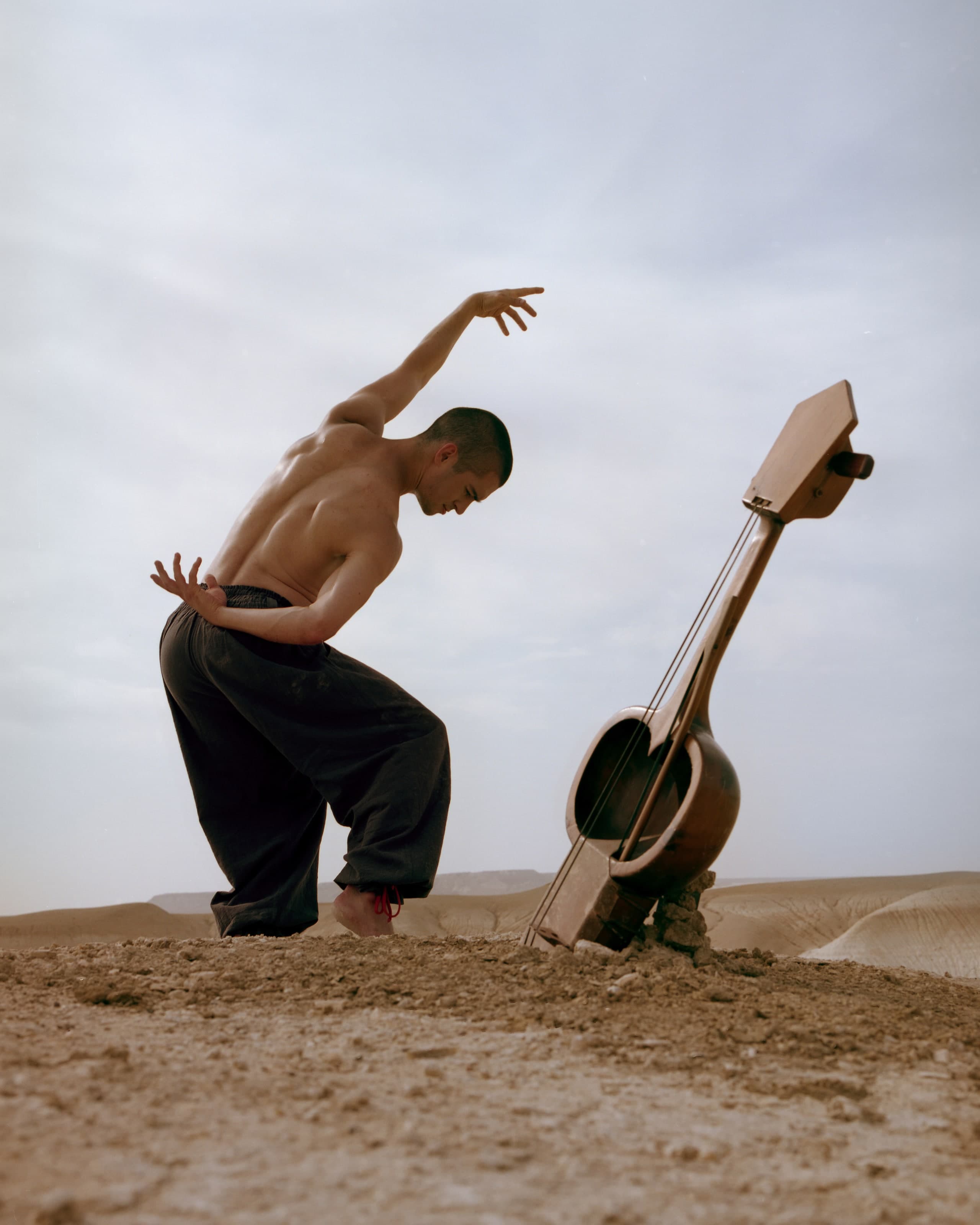Kolya Bagdasaryan moving beside a string instrument in the Bozzhyra landscape.